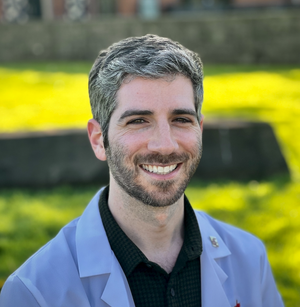 Sam Urkov, DNP, FNP-C, AQH, smiling outdoors in front of a green landscape